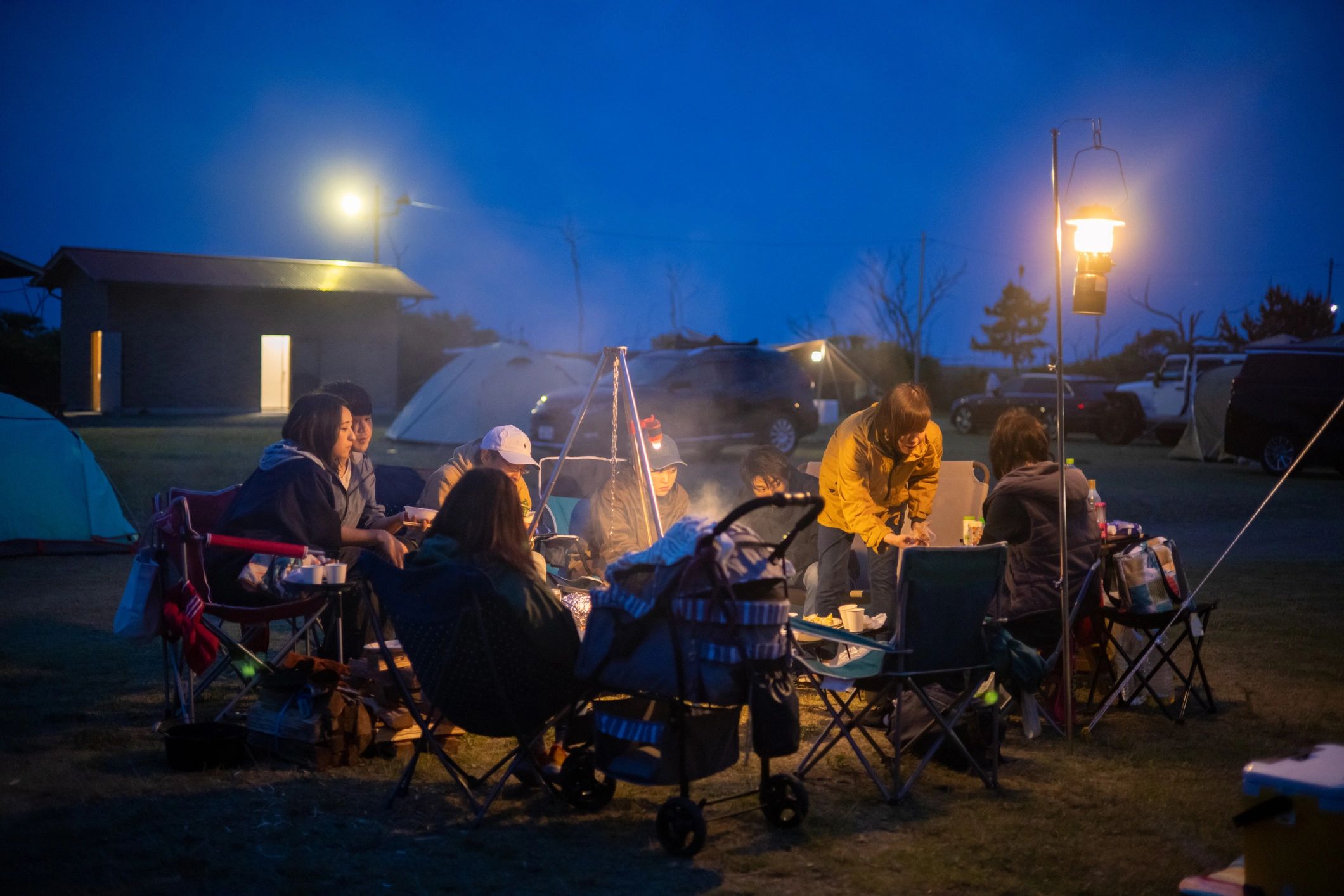 Families camping together at night and enjoying a meal outdoors