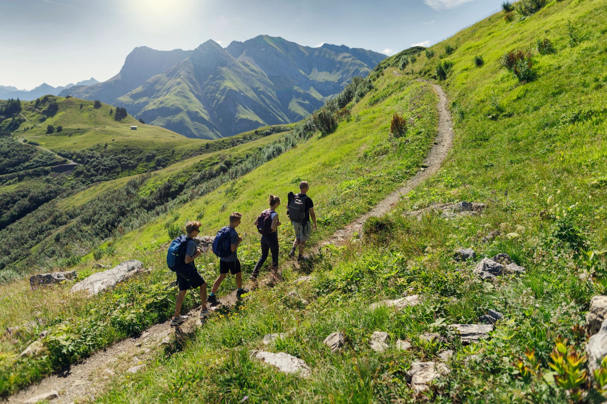 Family and teens hiking on a mountain trail
